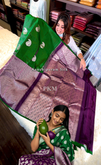 Woman holding a green and purple saree with visible branding in a store setting.